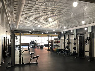 Interior of Post Rock Fitness in downtown Lincoln, Kansas, after renovations, featuring modern fitness equipment, open workout space, restored historic ceiling details, and updated lighting.