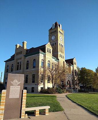 Front view of the historic Mitchell County Courthouse in Beloit, Kansas, following exterior restoration work completed in 2021, featuring restored stone masonry, the courthouse clock tower, and landscaped grounds.
