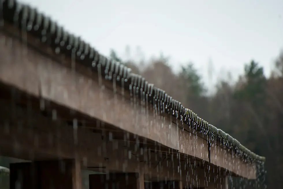 Rainwater dripping from a roof during a storm.