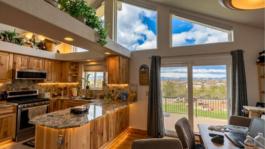 High-set architectural trapezoid windows left completely uncovered above an open kitchen to display a vivid blue sky filled with clouds — BCC of Denver Colorado.; Get weather-resistant outdoor shades from Blind Corners & Curves serving Aurora, Steamboat Springs, and Durango.;