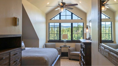 A charming attic bedroom featuring high architectural triangle and trapezoid windows left uncovered to display scenic mountain and forest views — BCC of Denver Colorado.; Achieve perfect light-filtering options for uniqueness with help from Blind Corners & Curves in Aurora, Steamboat Springs, and Breckenridge.;