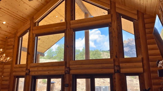 Custom light filtering honeycomb shades perfectly fitted and fully closed over large angled trapezoid windows in a log cabin home — Blind Corners & Curves of Denver Colorado.; Professional cordless operation for shaped windows available from Blind Corners & Curves in Denver, Grand Lake, and Breckenridge.; 