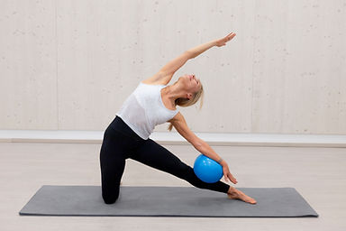 Pilates Trainerin auf einer Yoga Matte mit einem blauen Ball