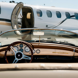 Porsche Speedster parked in front of an MPI Jet private aircraft on the Monterey airport tarmac