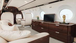 Interior of a luxury private jet featuring the FIFA World Cup trophy displayed on a leather seat during a California travel experience.