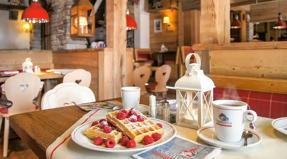 Waffeln mit Himbeeren auf Holztisch in rustikalem Café mit roten Lampen. Gemütliche Atmosphäre im edelweiss uriges Wirtshaus.