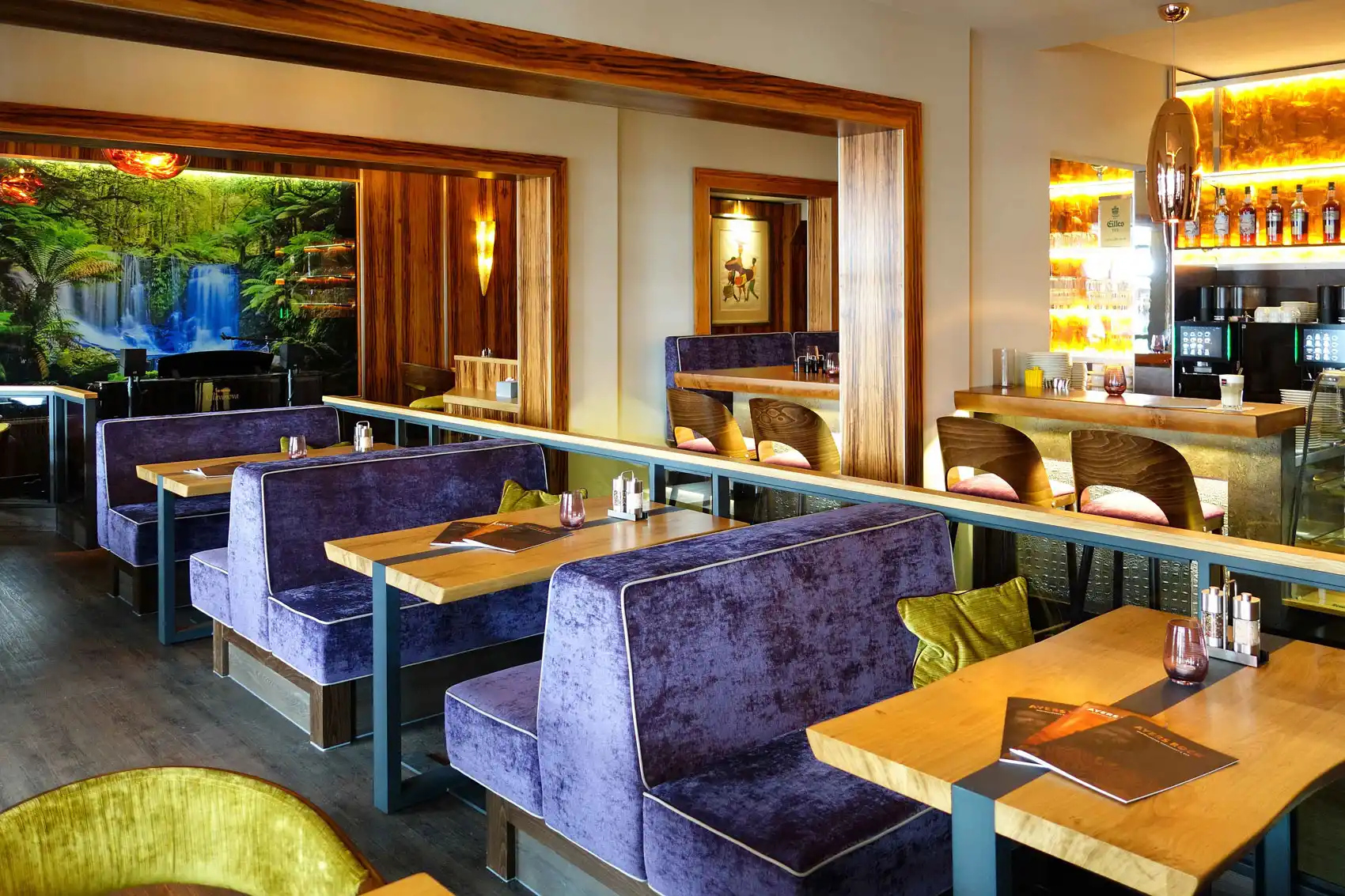 Modernes Restaurant mit gemütlichen, lila Sitzecken und großem Wandbild "Horseshoe Falls" Tasmanien