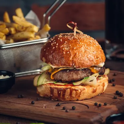 Hausgemachter Burger mit Pommes im Ayers Rock Restaurant Dresden – belegt mit Käse, Gurke und Zwiebeln