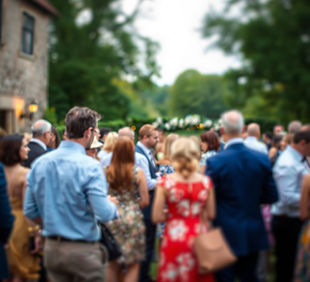 a gathering of people outside mingling at a wedding with a blurred picture.jpg