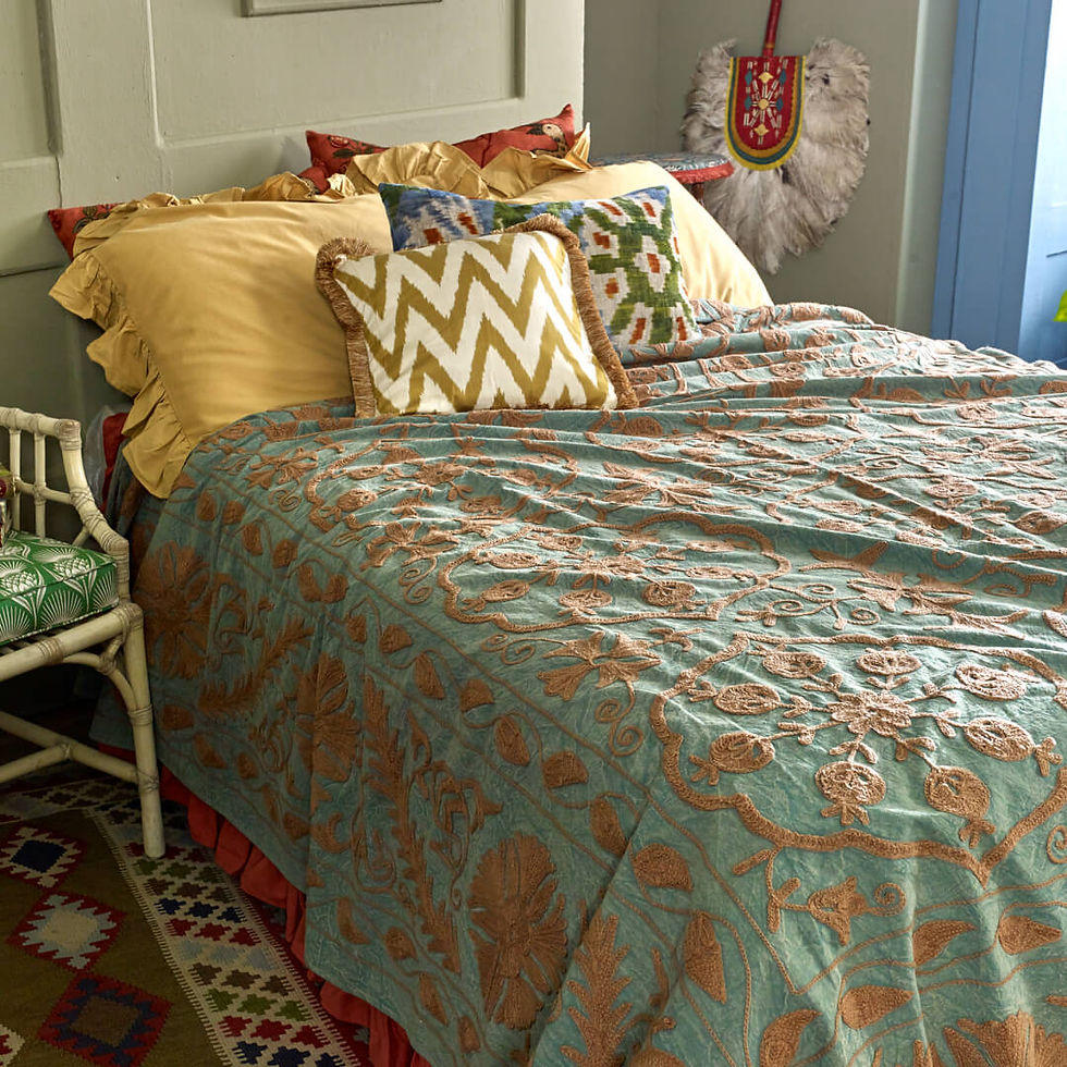 Green embroidered Suzani bed throw in blue styled bedroom
