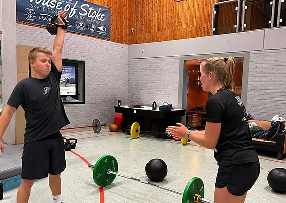 Two fit athletes performing a workout, while one is doing the exercise and the other one is pushing her partner.