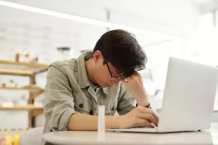 salarié qui s'ennui à son bureau en se tenant la tête