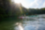 A group of people on kayaks on Tellico Lake with forest in the background.
