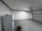 Wide garage view showing painted walls and ceiling, overhead lighting, and a speckled coated floor