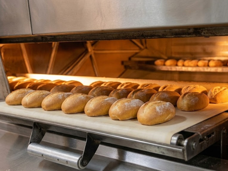 Brick oven filled with freshly baked artisan bread loaves at Cardinal Bakery, showcasing traditional baking and crisp golden crusts