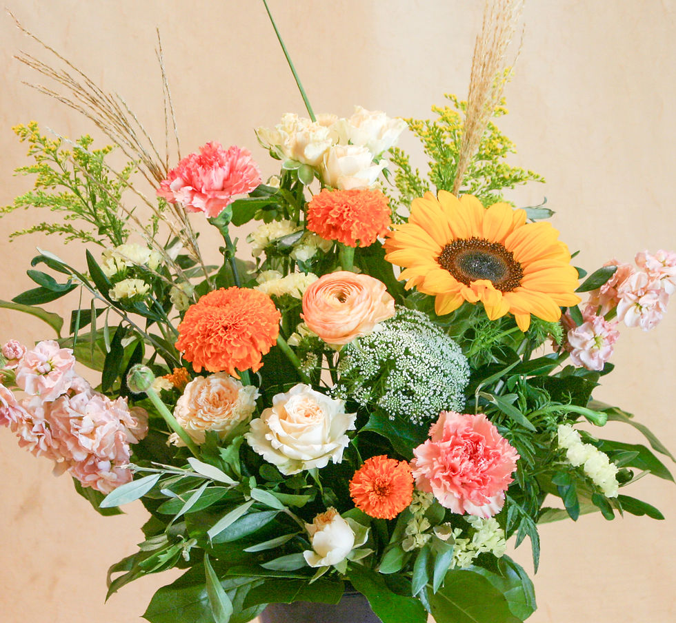 Fresh flower arrangement with summer blooms like marigolds, sunflowers,  garden spray roses, stock in a blue vase