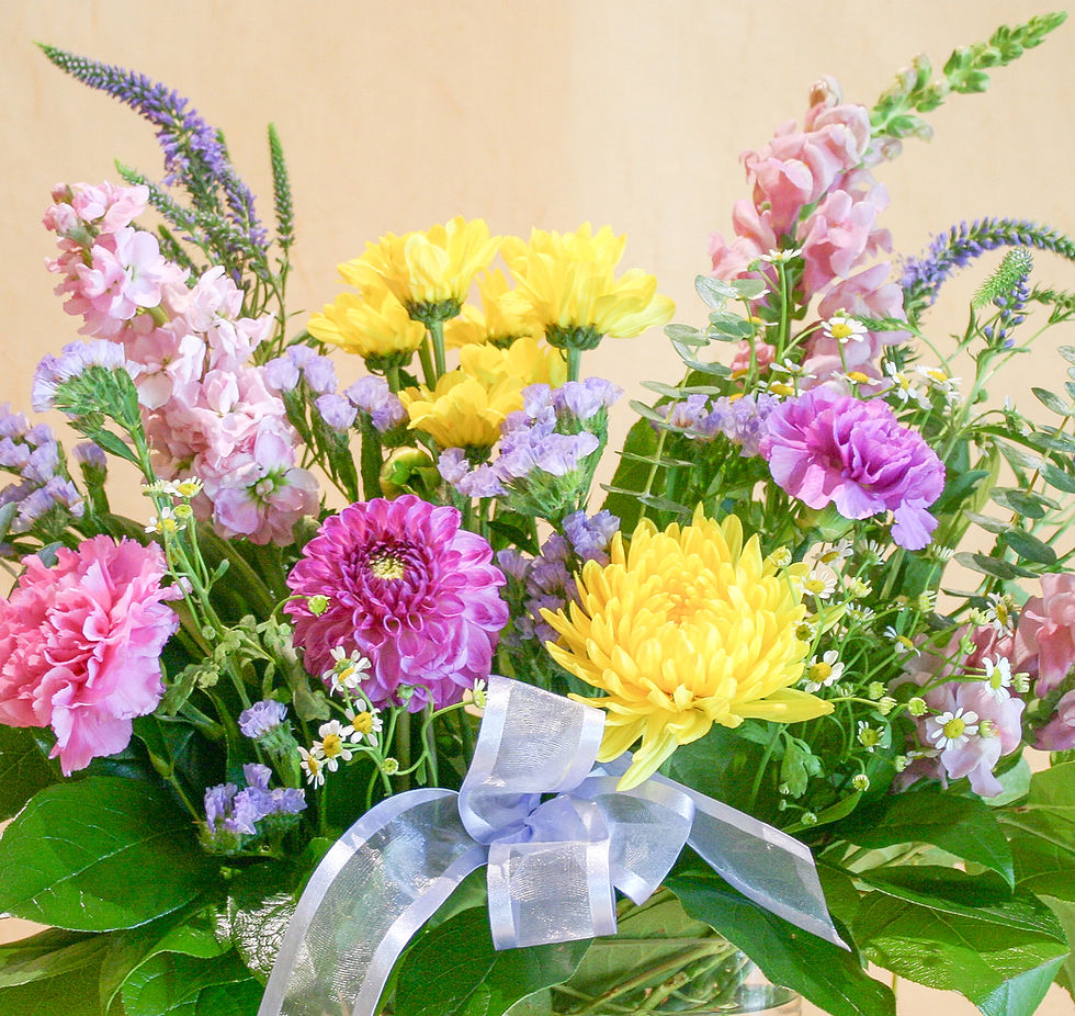 Floral arrangement with vibrant yellow & lavender  blooms with spiral eucalyptus in a clear class vase