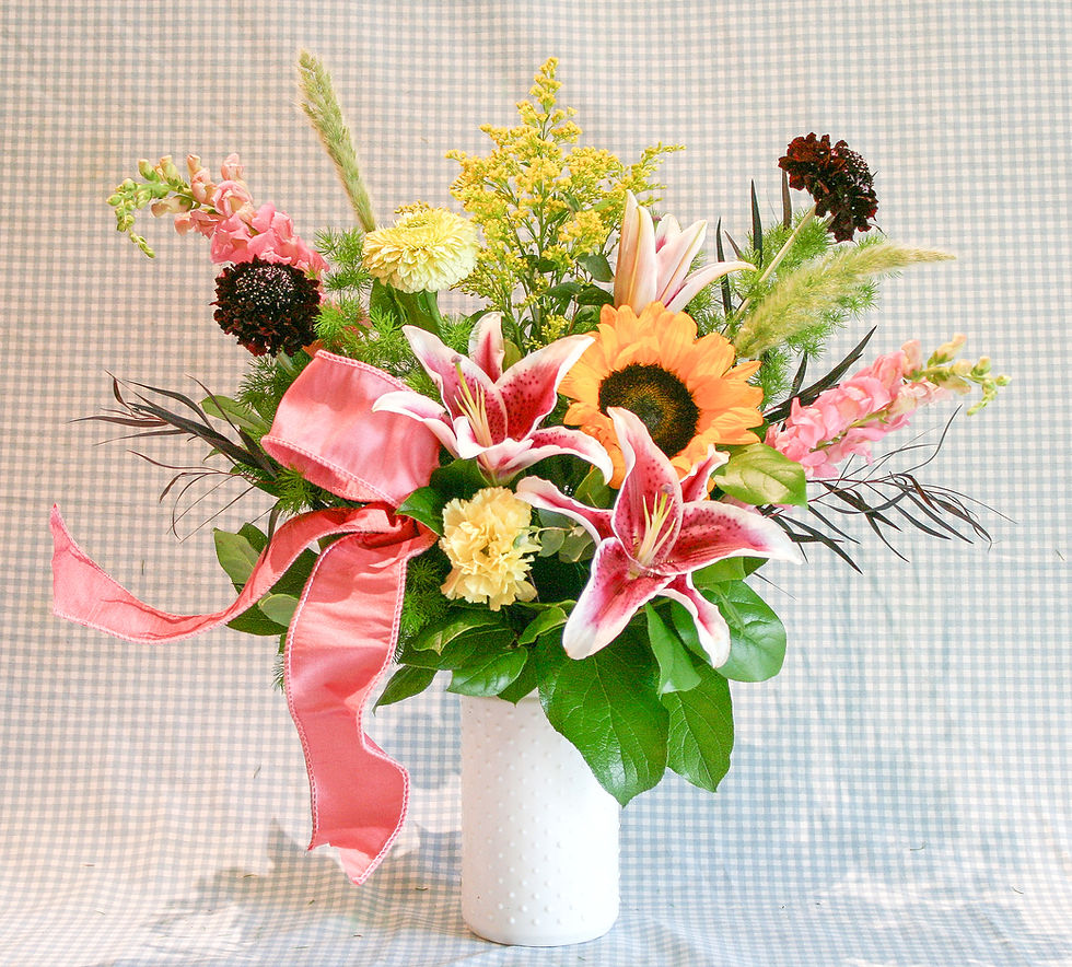 Fresh Flower arrangement lilies, snapdragon, gerbera, carns, scabiosa, solidago, sunflower in a tall milk glass vase