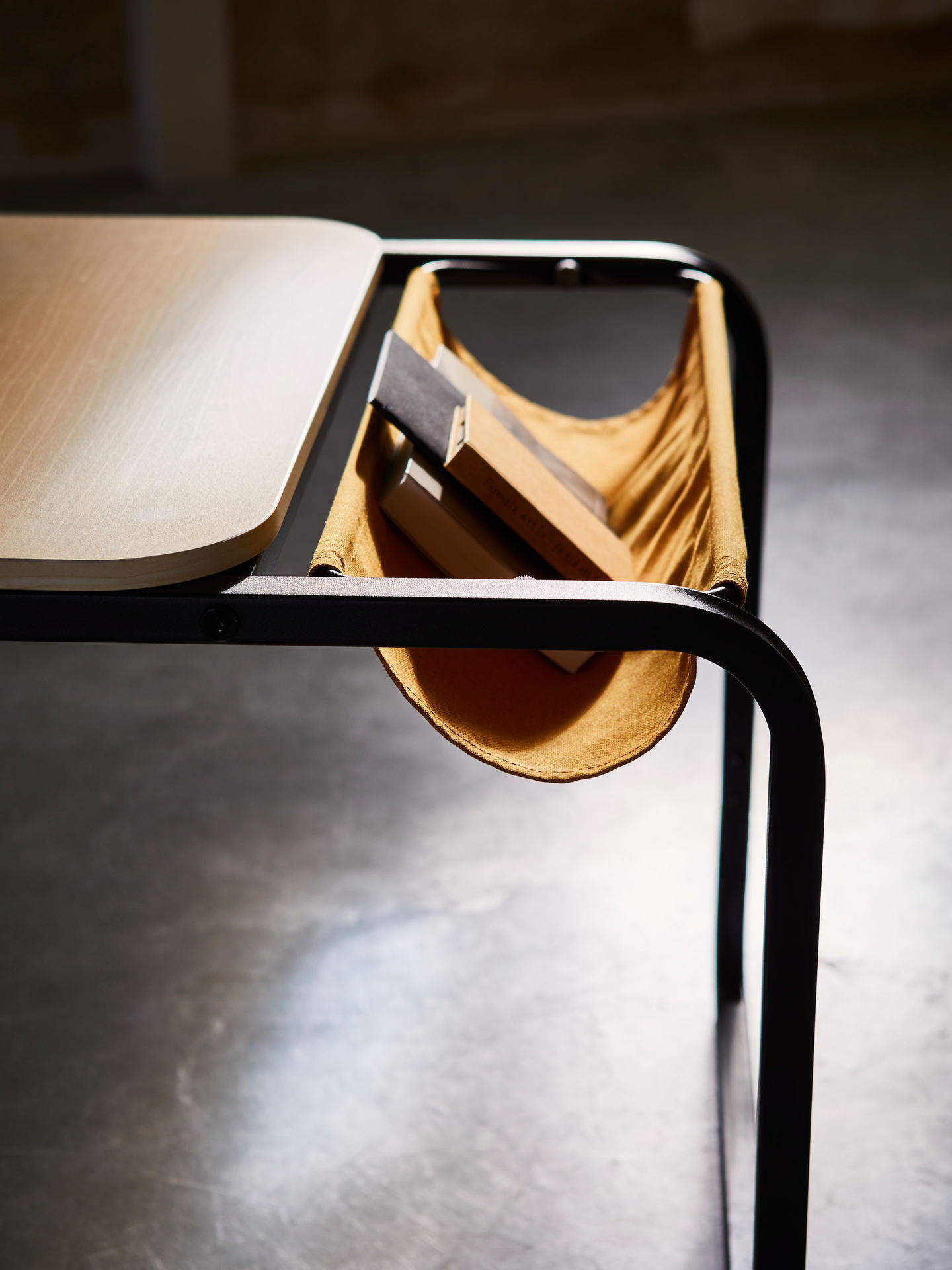 Olseröd in action—a sleek desk with a wooden top and metal frame, featuring a fabric sling for storage. A Scandinavian-inspired workspace balancing style and practicality, perfect for modern interiors.