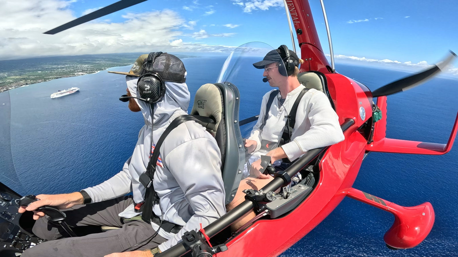 Guest flying an open-air gyroplane low over the ocean