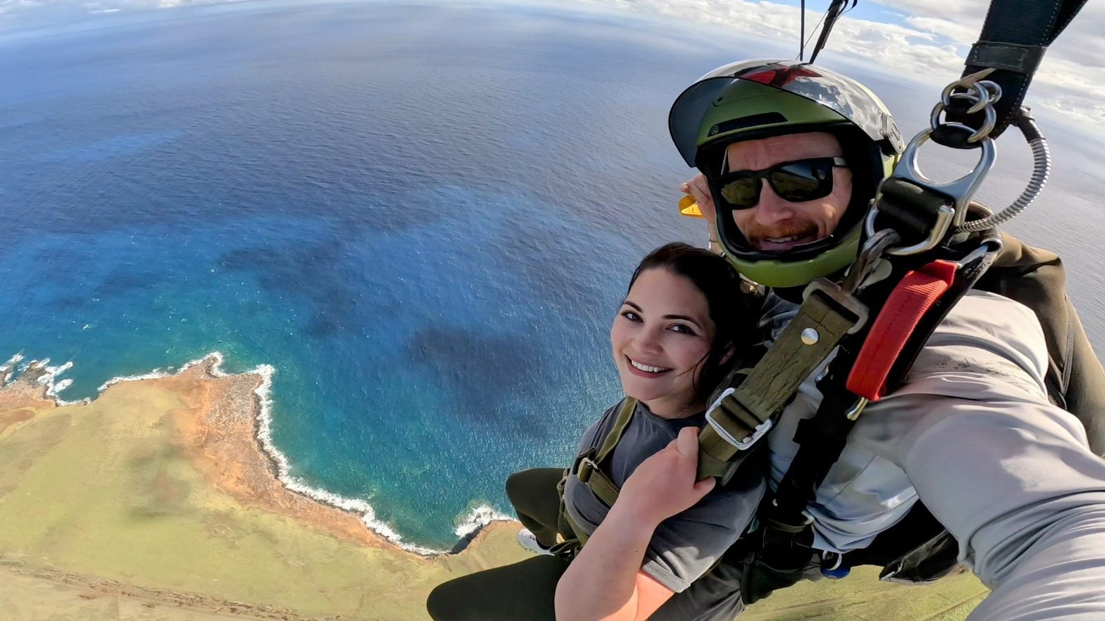 Couple smiling together under a parachute over the ocean