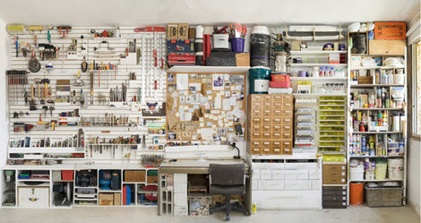 קיר מלא בציוד סטודיו, חומרים, מגירות, וכלים – מחסן אמנות מאורגן.
