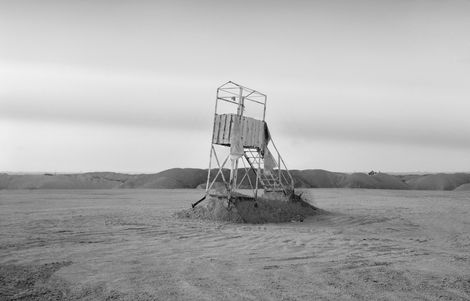 צילום נוף מדברי עם מבנה מתכתי דמוי מגלשה או סולם עומד על תל חול.