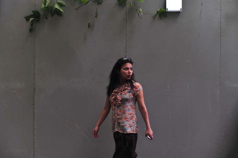  Photo of a woman walking past a gray exterior wall – isolated and still