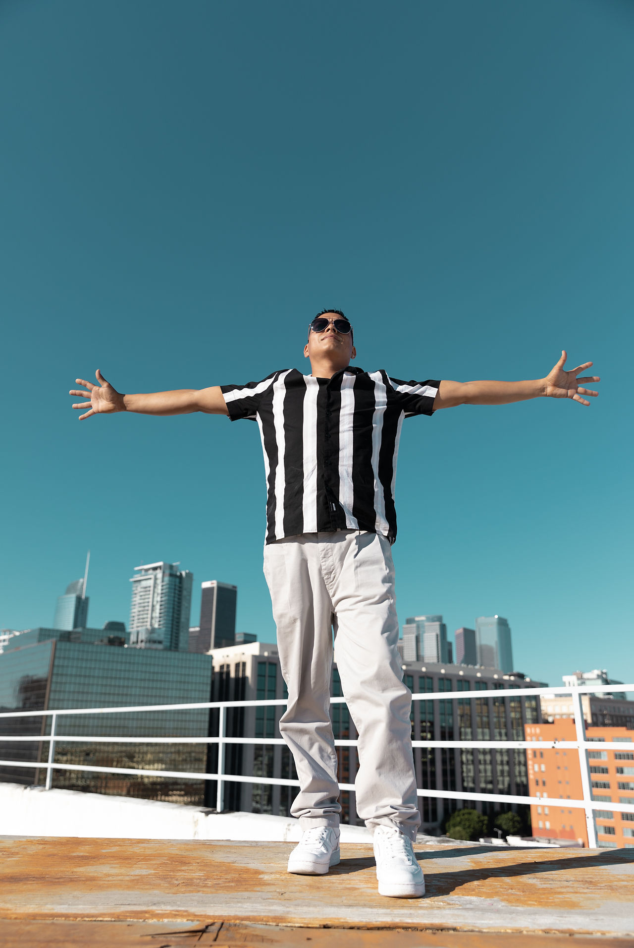 Musician stands with arms stretched for music video shoot with Erin and Jake Photography in Los Angeles.