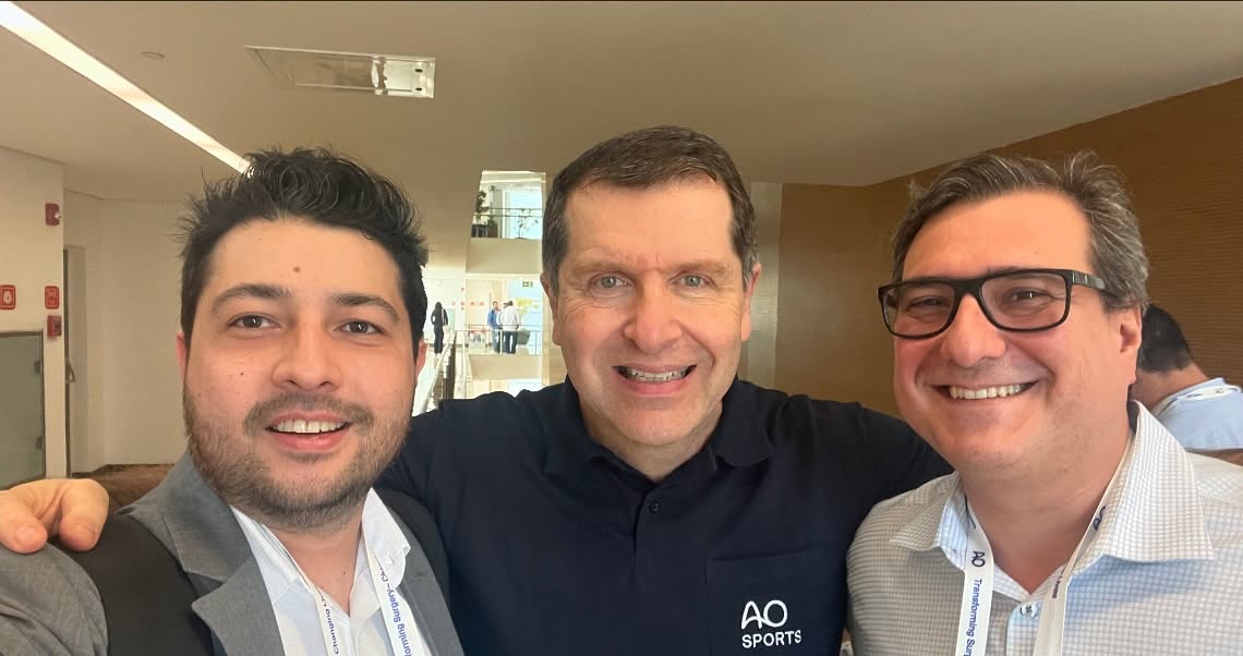 Três homens sorrindo em evento