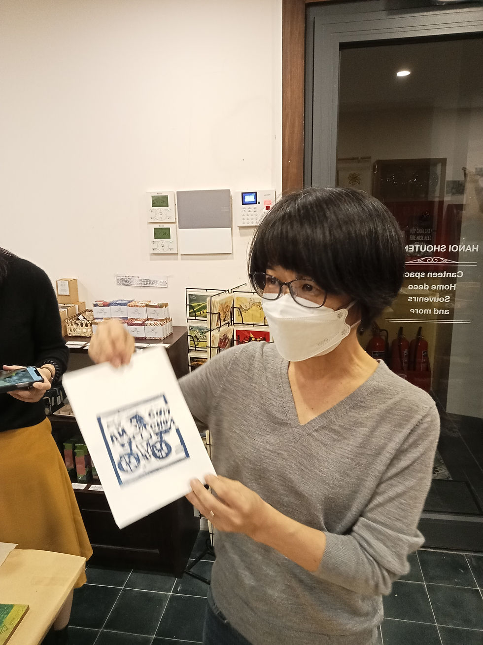 Participant proudly holding finished woodcut print at Em Hanoi workshop, Hanoi Vietnam