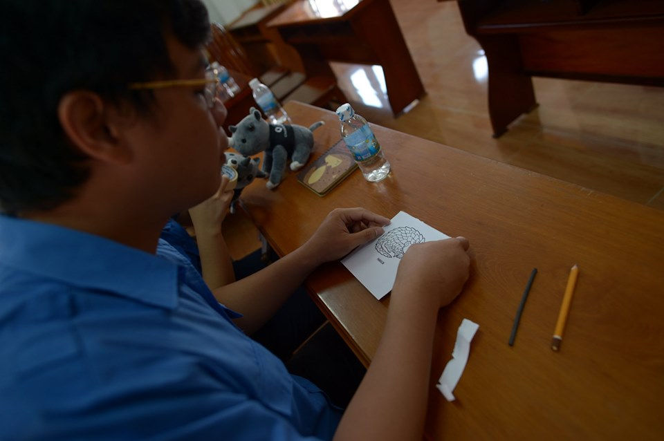 Participant sketching pangolin design for woodcut print at WildAid wildlife awareness workshop, Nha
