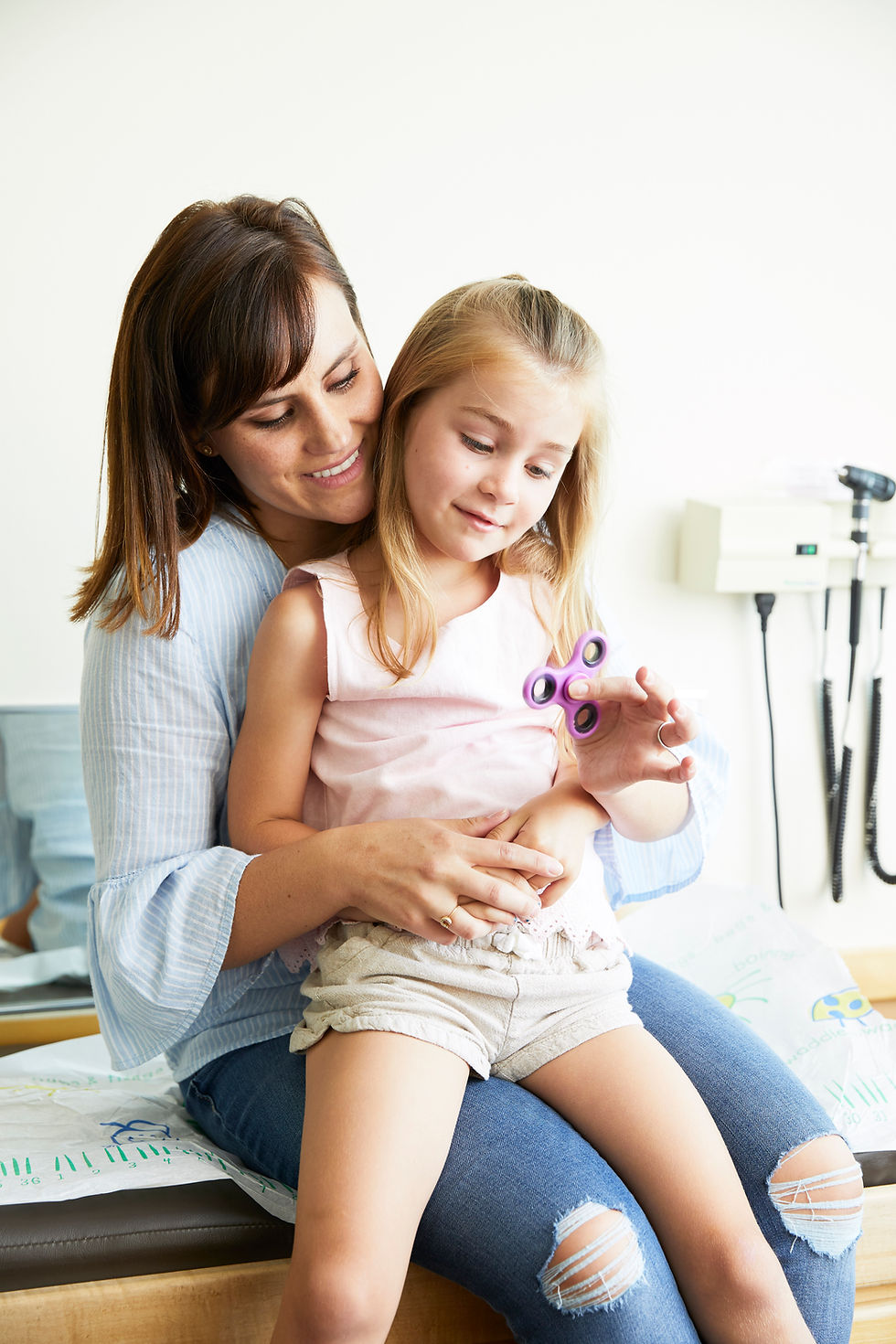child being held by mom at the doctor playing