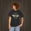 Thumbnail: Girl wearing a black classic car t-shirt featuring a green background with a red wings circle design.