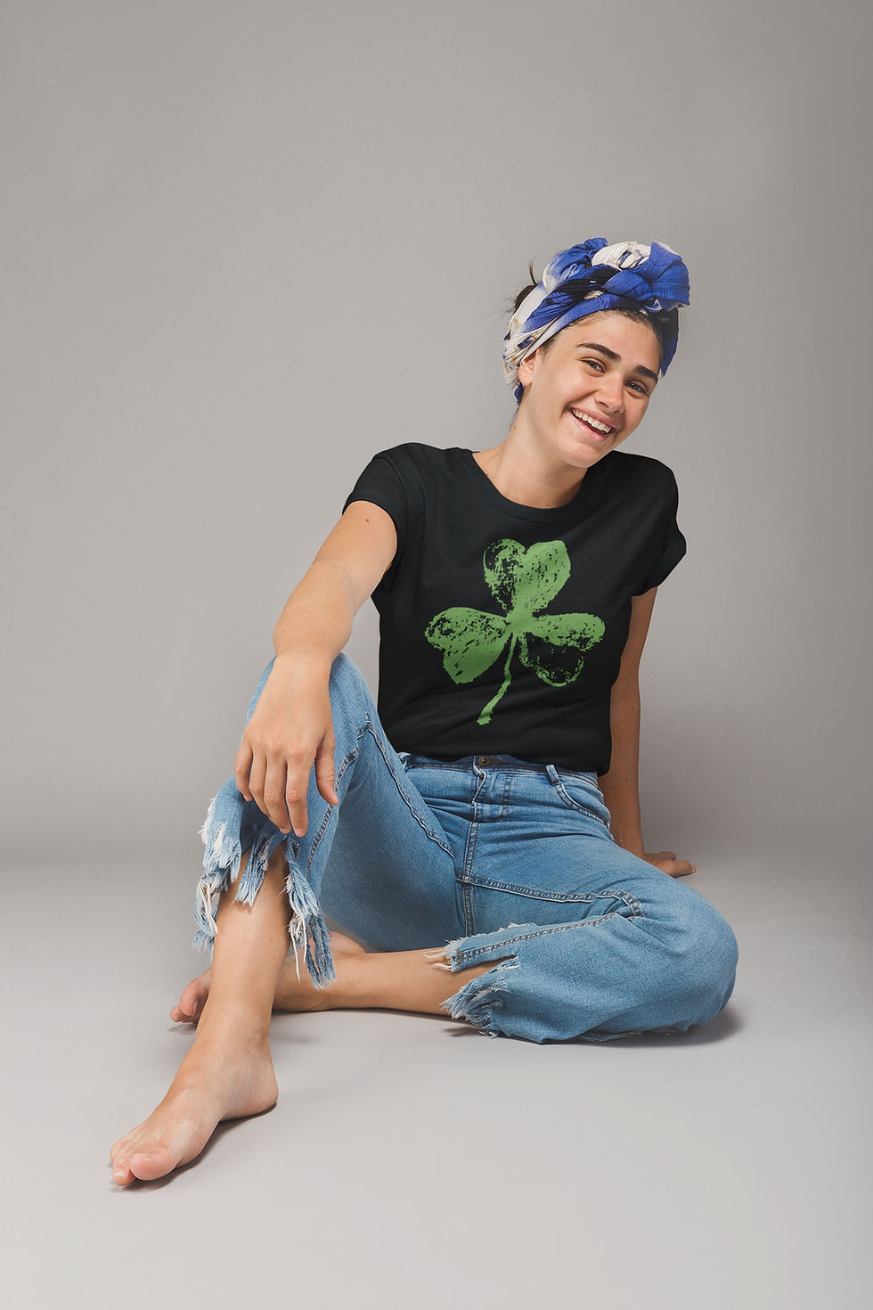 Woman wearing a black t-shirt featuring a large, faded or distressed green three-leaf shamrock graphic