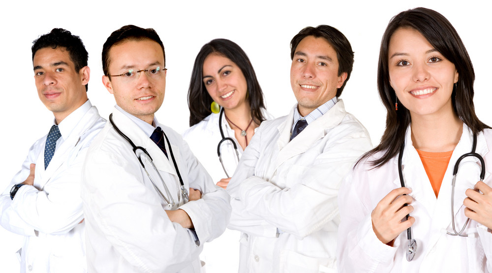 friendly young doctors smiling over a white background - focus is on the female doctor on the right
