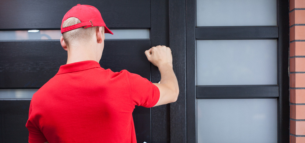 Back view of a delivery man knocking on the clients door