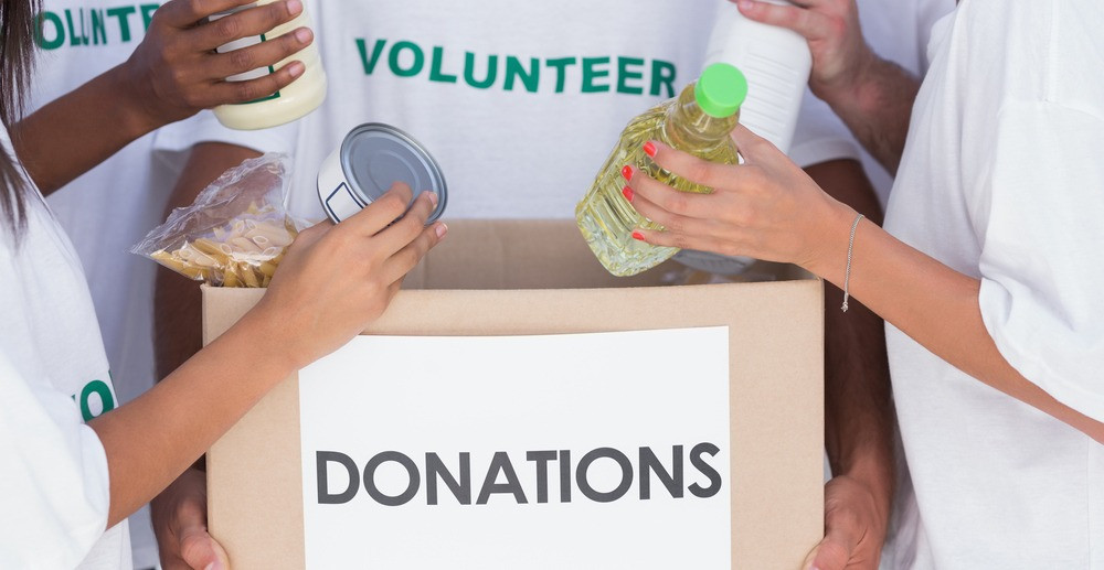 Group of volunteers putting food in donation box
