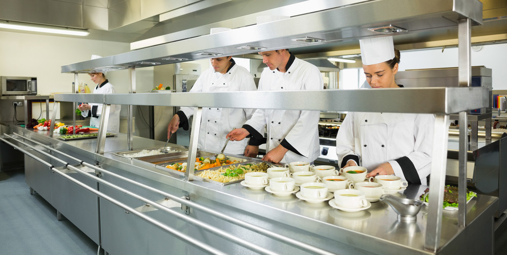 Four chefs working in a big kitchen at service time