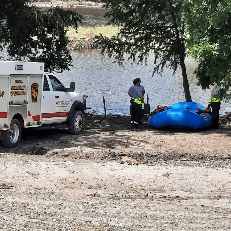 Emergency personnel prepare for water rescue operations along the riverbank in Kerrville, TX, equipped with a rescue raft and support vehicle.