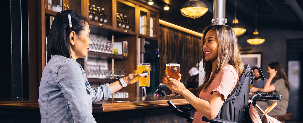 Image of a lady in a wheelchair having a beer with a friend