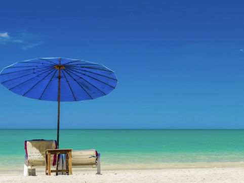 Umbrella shades lounge chairs on a sandy beach. An opportunity to take a moment for yourself on holiday