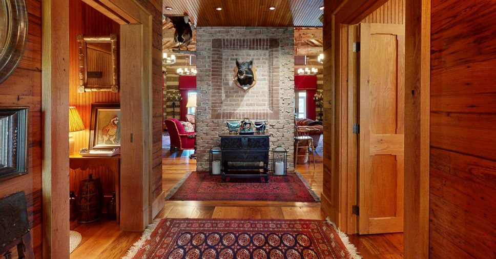 Entry hallway of the Duvall Farm Main Lodge in Easton, Maryland, leading to a stone fireplace with wood walls and warm lighting.