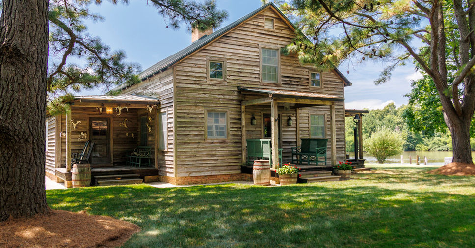 Exterior, Tennessee Pioneer cabin entry The exterior is classic and understated, featuring weathered wood beams and a full wraparound screened porch that overlooks a peaceful pond.