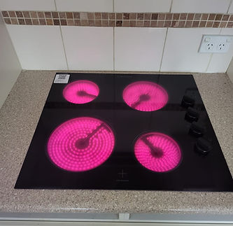 Electrician inspecting electric stovetop with glowing burners