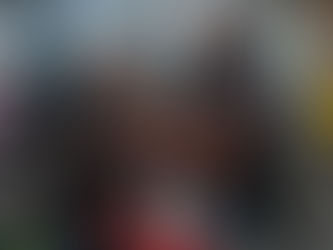 Man exercising on a rowing machine, trainer kneeling beside him. Gym setting, bright colors from machines and art. Focused and determined mood.