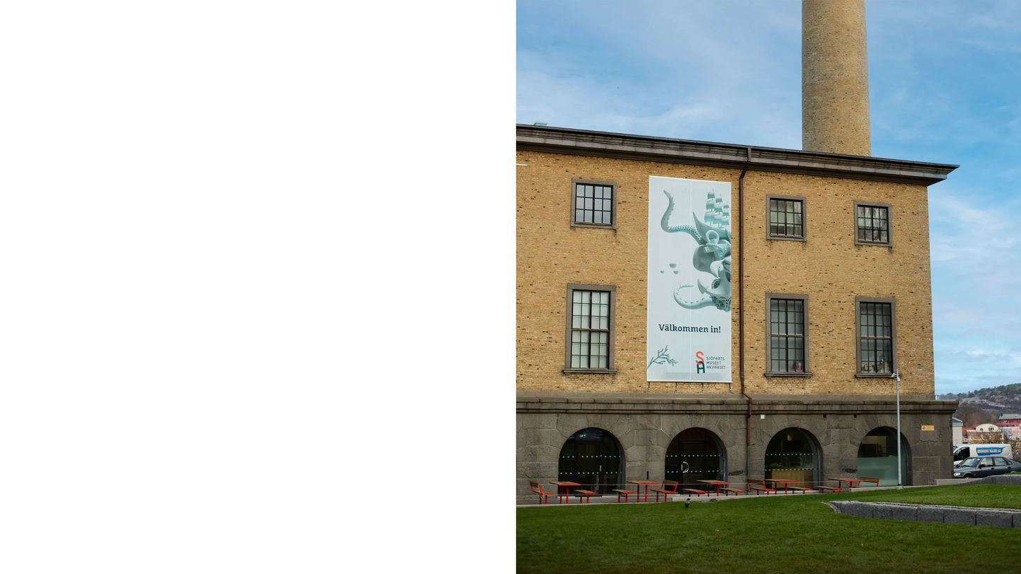 Vy av Sjöfartsmuseet Akvariets fasad med en vepa som välkomnar besökare. Texten 'Välkommen in!' syns tydligt tillsammans med en illustration av maritima element.
