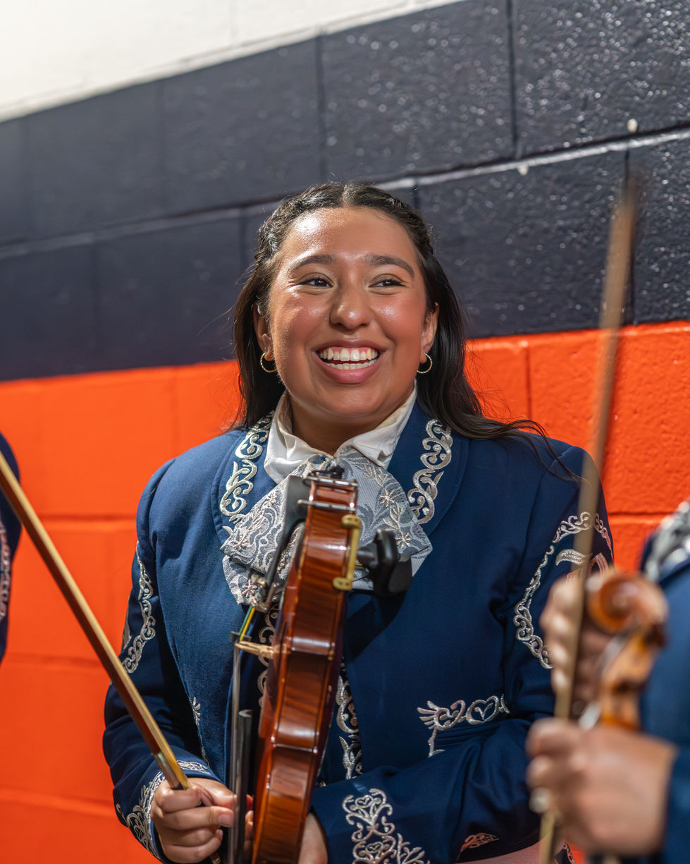A violinist smiles as she looks at another member to her right