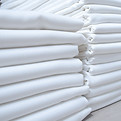 Stacks of folded white fabrics or sheets in a laundry. Cleaning service for institutions a