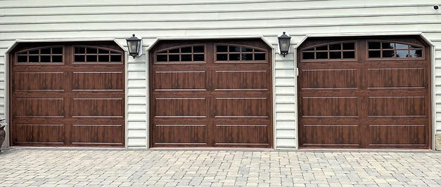 Three elegant wood-look garage doors with decorative upper windows installed on a New Jersey home